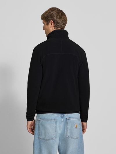 Männermodel trägt Fleecepullover mit Label-Stitching von The North Face in Schwarz, Regular Fit, Stehkragen, Rückenansicht, Ganzkörperansicht Rückansicht