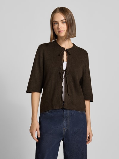 Frauenmodel trägt Regular Fit Strickjacke mit Schnürung Modell 'SIMONI' von ONLY in Dunkelbraun, lockere Passform, Damen Strickjacke, Nahaufnahme Oberkörper.