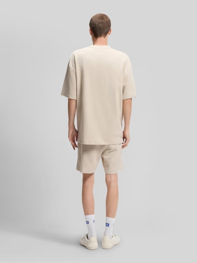 Männermodel trägt Relaxed Fit T-Shirt aus Baumwoll-Mix Modell 'NUWAFFLE' von HUGO in Optik: Unifarben mit Struktur-Muster, Label-Stitching-Applikation, Rundhals-Ausschnitt und Kurzarm, Material: Baumwoll-Mix, Ganzkörperansicht Rückansicht.