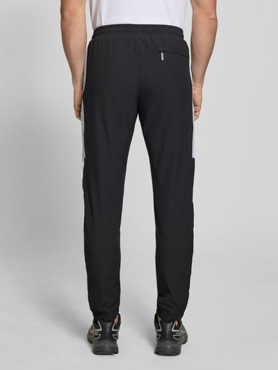 Männermodel trägt Sweatpants mit Logo-Stitching Modell 'CASPIO' von SERGIO TACCHINI in Schwarz, Material-Mix mit Stretch-Anteil, Eingrifftaschen, körpernaher Schnitt, elastischer Bund mit Kordelzug, elastische Abschlüsse, Ganzkörperansicht Rückansicht.