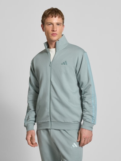 Männermodel trägt Sweatanzug mit Label-Stitchings von adidas Sportswear aus Baumwoll-Mix, Regular-Fit, hellblau, Nahaufnahme Oberkörper.