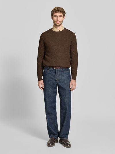 Männermodel trägt Regular Fit Pullover aus Baumwoll-Woll-Mix von GANT in Braun, kombiniert mit blauer Jeans, Ganzkörperansicht von vorne.