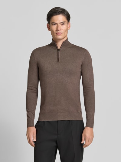 Männermodel trägt braunen Troyer mit Label-Applikation von MARKUP, Viskose-Mix, gerader Schnitt, gerippte Abschlüsse, Ganzkörperansicht von vorne.