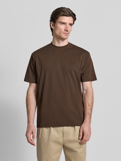 Männermodel trägt Regular Fit T-Shirt aus reiner Baumwolle Modell 'Baine' von WOODBIRD in Braun mit Rundhalsausschnitt, Nahaufnahme Oberkörper.