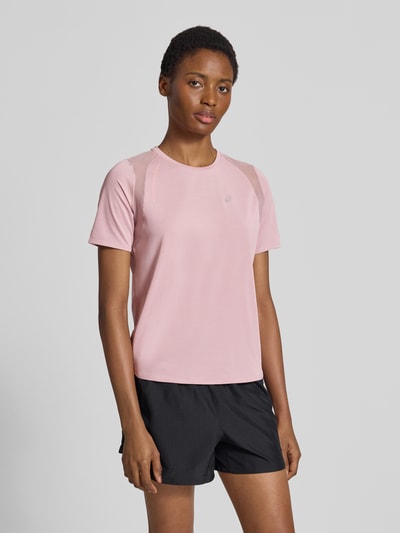 Frauenmodel trägt Regular Fit T-Shirt mit Stretch-Anteil Modell 'Road' von ASICS TIGER in Rosa mit reflektierendem Logo, Nahaufnahme Oberkörper.