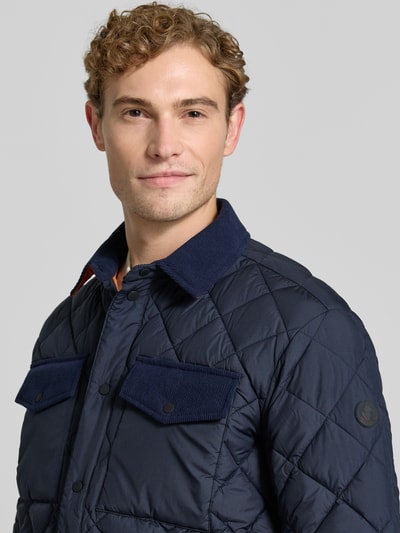 Männermodel trägt Regular Fit Jacke in Stepp-Optik Modell 'FIRMIN' von Save The Duck, dunkelblau, Brusttaschen, Nahaufnahme Oberkörper.