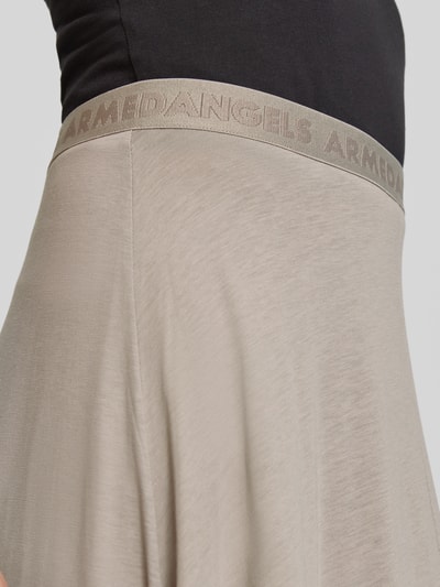 Frauenmodel trägt Loose Fit Midi-Rock aus Lyocell-Baumwoll-Mix Modell 'ILENIAA LARAA' von Armedangels in Beige mit feiner, glatter Textur, Damen Midi-Rock von Armedangels, Nahaufnahme Oberkörper.