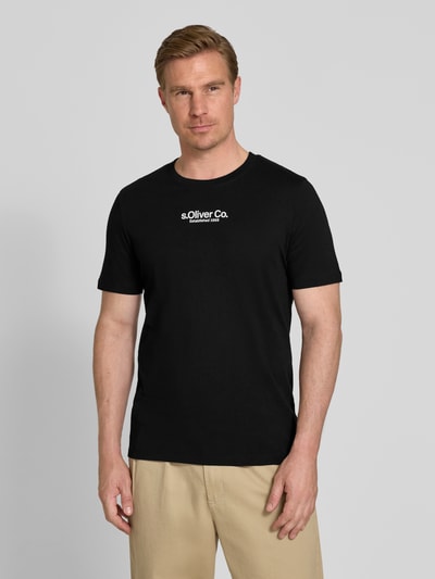 Mężczyznęmodel nosi Regular Fit T-Shirt aus reiner Baumwolle von s.Oliver RED LABEL, czarny, okrągły dekolt, krótki rękaw, nadruk z logo, gładka dzianina jersey, widok na cały korpus z przodu.