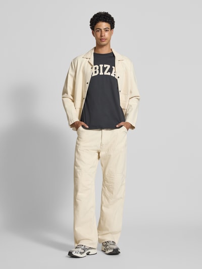 Männermodel trägt Relaxed Fit T-Shirt aus reiner Baumwolle Modell 'RICO' von Only & Sons, unifarben, Motiv-Print, Ganzkörperansicht von vorne