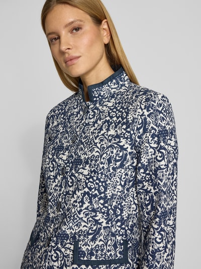 Vrouwenmodel draagt Blazer met Stretch-Anteil und Pattentaschen van WHITE LABEL in blauw-wit patroon, elastische materiaalmix met katoen, licht getailleerde pasvorm, opstaande kraag, doorlopende knoopsluiting en klepzakken, detailopname bovenlichaam.
