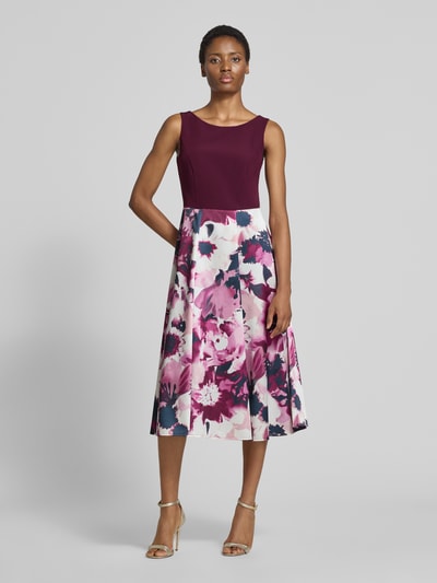 Frauenmodel trägt Tailliertes Cocktailkleid mit Allover-Muster von Vera Mont in Dunkelrot mit floralem Muster in Rosa und Weiß, Ganzkörperansicht von vorne. Damen Cocktailkleid von Vera Mont.