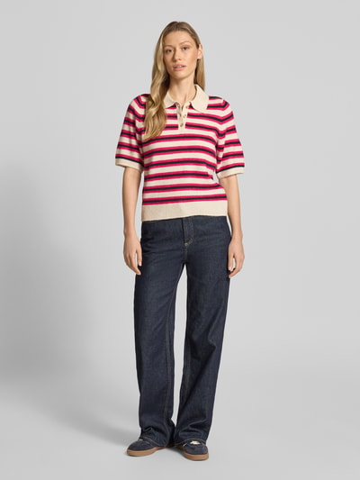 Frauenmodel trägt Regular Fit Strickpullover mit Woll-Anteil Modell 'CANNA' von Vero Moda, mehrfarbig gestreift, Polokragen, V-Ausschnitt, gerippte Abschlüsse, Stricktextur, Ganzkörperansicht von vorne.