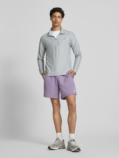 Männermodel trägt Regular Fit Sweatshirt mit Troyer-Kragen von New Balance in Grau, Elastischer-Material-Mix, Logo-Print, Ganzkörperansicht von vorne. Rückenlänge bei Größe M: 69 cm.