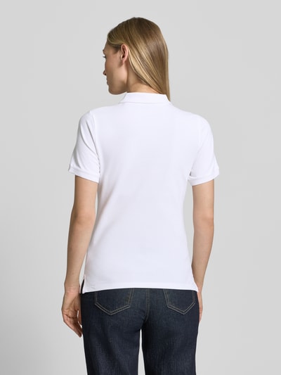 Frauenmodel trägt weißes Slim Fit Poloshirt mit Label-Stitching von Gant aus Baumwoll-Elasthan-Mix, Rückenlänge 59 cm, Ganzkörperansicht Rückansicht.