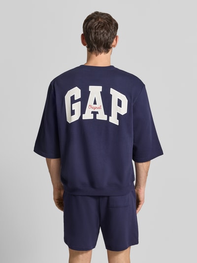 Männermodel trägt T-Shirt mit Rundhalsausschnitt und Logo-Print von GAP in Dunkelblau, Baumwoll-Mix, Loose Fit, Rückenansicht, Ganzkörperansicht Rückansicht.