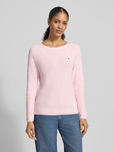 Vrouwenmodel draagt Regular Fit Pullover aus reiner Baumwolle van Tommy Hilfiger, effen lichtroze ribgebreid katoen, logo-stitching, ronde hals, lange mouw, geribde boorden, vooraanzicht bovenlichaam.