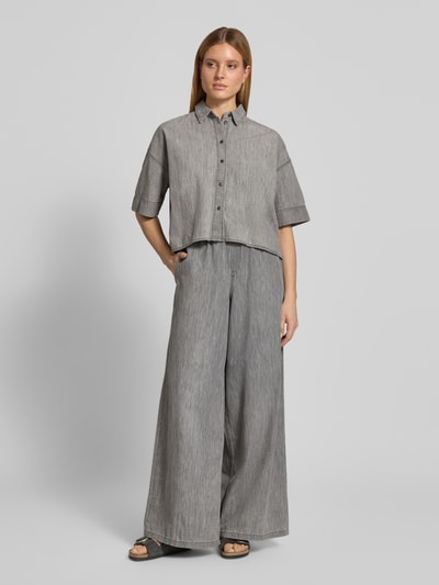 Kobiece modelka ma na sobie bluzka jeansowa Boxy Fit model 'YARIKA' z bawełny od Drykorn, szara, z kołnierzykiem koszulowym i listwą guzikową, długość tyłu 53 cm, rękawy 22 cm, pudełkowy krój, widok całej sylwetki z przodu.