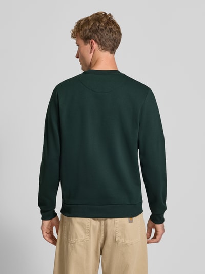 Männermodel trägt Regular Fit Sweatshirt mit Baumwoll-Anteil Modell 'Bradley' von JACK & JONES in Dunkelgrün, glatte Struktur, Ganzkörperansicht Rückansicht. Herren Sweatshirt mit Rundhalsausschnitt, Langarm, gerippten Abschlüssen und Logo-Label. Rückenlänge bei Größe M: 66 cm, Ärmellänge: 64 cm, Material-Mix.