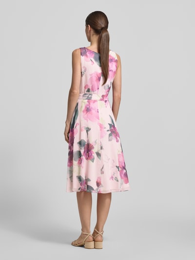 Frauenmodel trägt Knielanges Cocktailkleid mit Bindegürtel von Vera Mont aus Chiffon mit Taillierter Schnitt, Wasserfall-Ausschnitt, floralem Muster, Knielänge, Rückenlänge 104 cm bei Größe 36, Brustweite 40 cm, Ganzkörperansicht Rückansicht.