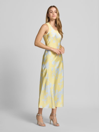 Frauenmodel trägt Fließendes Etuikleid aus Satin Modell 'SUB' von MAX&Co., Optik: Allover-Muster, Maxi-Länge, Rundhals, Lingerie-Stil, Crépon-Doppelbesätze, asymmetrische Diagonalnähte, breite Träger, ungefütterte Passform, glatte und glänzende Satin-Materialverarbeitung, Pastellgelb mit blassem Muster, Ganzkörperansicht von vorne.