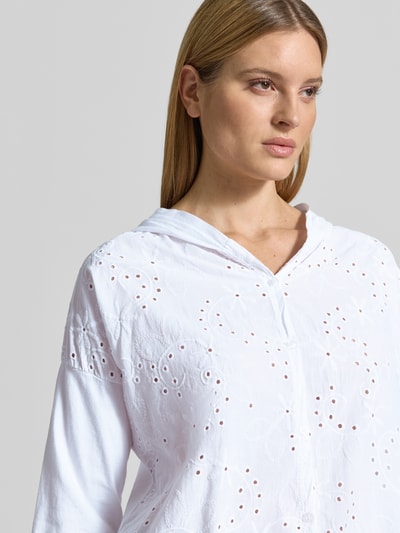 Frauenmodel trägt Bluse mit Kapuze Modell 'Is4aa' von ZABAIONE aus reiner Baumwolle mit Lochstickerei, Nahaufnahme Oberkörper.