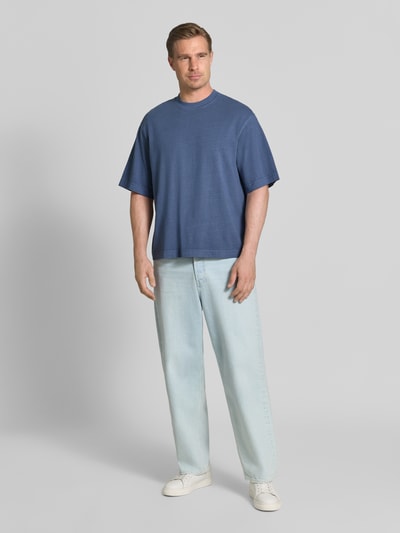 Männermodel trägt Boxy Fit T-Shirt aus reiner Baumwolle Modell 'CORY' von Selected Homme in Blau, kombiniert mit hellen Jeans, Ganzkörperansicht von vorne, Herren T-Shirt von Selected Homme.