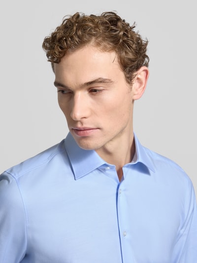 Męski model nosi Slim Fit Businesshemd aus Baumwoll-Mix od OLYMP, efekt: jednolity kolor, kołnierzyk typu kent, listwa guzikowa na całej długości, mankiety sportowe, oddychający materiał, łatwa pielęgnacja, szybkoschnący, wykończenie: splot twill, mieszanka bawełny, rozmiar 40 – długość tyłu 80 cm, szerokość ramion 45 cm, długość rękawa 69 cm, zbliżenie na górną część ciała