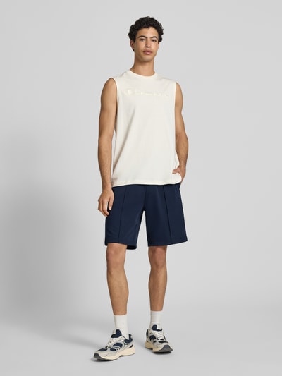 Männermodel trägt Bermudas mit elastischem Bund und Label-Stitching von CHAMPION aus Baumwoll-Mix, Regular-Fit, marineblau, Ganzkörperansicht von vorne.