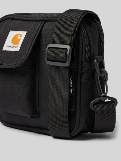 Productfoto, zwarte Crossbody Bag met logo-patch van Carhartt Work In Progress, hoofdvak met ritssluiting, verstelbare schouderband, afneembare schouderband, Breedte maat 1: 17 cm, Lengte maat 1: 18 cm, Diepte maat 1: 6 cm, bandlengte maat 1: 80 cm, grove textuur, rechthoekige vorm
