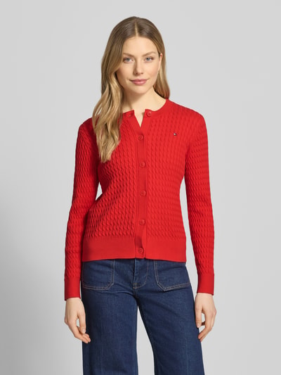 Frauenmodel trägt Slim Fit Strickjacke aus reiner Baumwolle von Tommy Hilfiger in Optik: Unifarben, Zopfmuster, Logo-Stitching, Rundhals, Langarm, Knopfleiste, Strick, Material: Reine Baumwolle, Ganzkörperansicht von vorne.