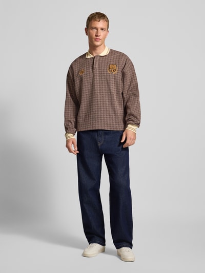 Męski model nosi Jeans z szeroką nogawką LANDON od Carhartt Work In Progress, ciemnoniebieska bawełna, przód cała sylwetka.