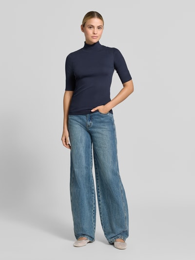 Frauenmodel trägt Slim Fit Longsleeve aus Baumwoll-Mix von Marc Cain in Dunkelblau, elastisches Material, Halbarm, Stehkragen, Ganzkörperansicht von vorne.