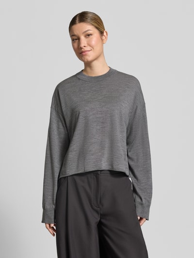 Frauenmodel trägt grauen Strickpullover aus Schurwolle Modell 'MALESE' von DRYKORN, Relaxed Fit, Rundhalsausschnitt, Ganzkörperansicht von vorne.