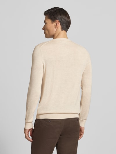 Männermodel trägt Strickpullover aus Woll-Mix mit V-Ausschnitt von Christian Berg Men in Beige, glatte Textur, Ganzkörperansicht Rückansicht, Regular Fit, gerippte Abschlüsse, Rückenlänge bei Größe M 71 cm, Ärmellänge 73 cm.