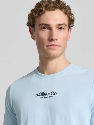Męski model nosi Regular Fit T-Shirt aus reiner Baumwolle von s.Oliver RED LABEL, efekt: jednolity kolor, krój regular fit, nadruk z logo, okrągły dekolt, krótki rękaw, bawełna, zbliżenie na górną część ciała.