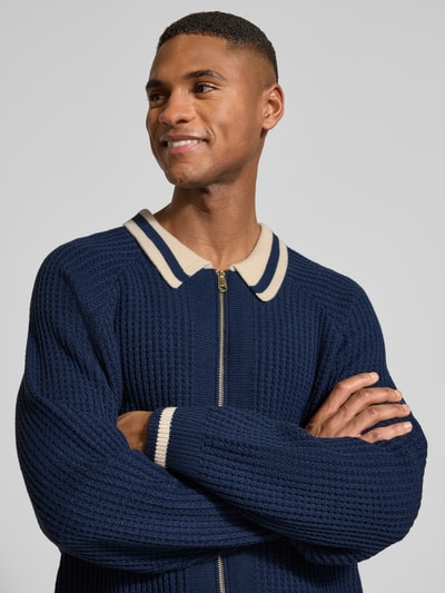 Männermodel trägt Relaxed Fit Jacke in Strick-Optik von BLKVIS in Dunkelblau mit Umlegekragen, Logo-Patch und Zweiwege-Reißverschluss, Nahaufnahme Oberkörper.