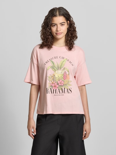 Frauenmodel trägt Boxy Fit T-Shirt aus reiner Baumwolle Modell 'LUCY' von Only in Optik: Unifarben mit Motiv-Print, Rundhals, Kurzarm, Ganzkörperansicht von vorne.