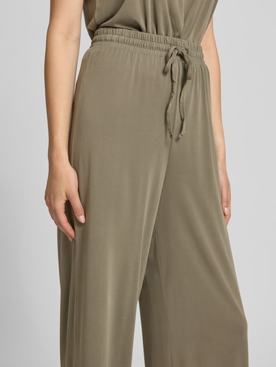 Frauenmodel trägt Weite Hose aus Viskose-Mix Modell 'ANORA' von PIECES in Olivgrün, fließender Stoff, Gummibund, Nahaufnahme Oberkörper. Damen Weite Hose von PIECES.
