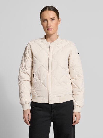 Vrouwenmodel draagt gewatteerd jack met opstaande kraag en knoopsluiting model 'ANGE2' van khujo in regular fit, kleuren lichtbeige en zwart, textuur doorgestikte naad, ruglengte maat S 59 cm, schouderbreedte 36 cm, borstwijdte 46 cm, mouwlengte 61 cm, ganzekörpervooraanzicht.
