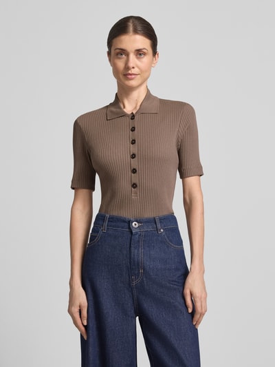 Modelka nosi koszulkę polo Slim Fit Poloshirt aus Baumwoll-Modal-Mix od Marc O'Polo, efekt: jednolity kolor, krój slim fit, aplikacja z wyhaftowanym logo, kołnierzyk polo, krótkie zapięcie na guziki, krótki rękaw, wykończenie materiału: prążkowana dzianina, mieszanka bawełny i modalu; całkowity widok z przodu.