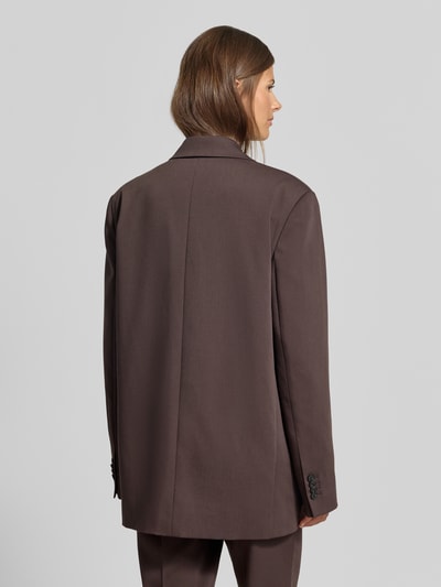 Frauenmodel trägt Oversized Blazer mit Viskose-Anteil von MYON in Braun, doppelreihig, Pattentaschen, Ganzkörperansicht Rückansicht.
