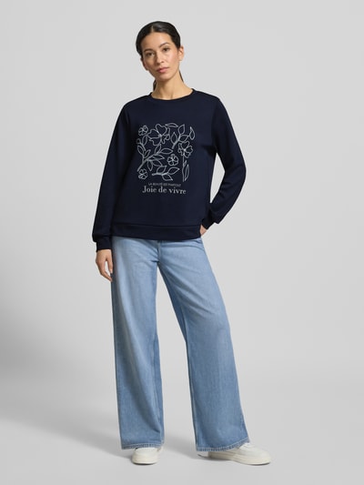 Frauenmodel trägt Sweatshirt mit Label-Print Modell 'BANU' von Soyaconcept, dunkelblau, gerippte Abschlüsse, lockerer Schnitt, Ganzkörperansicht von vorne.