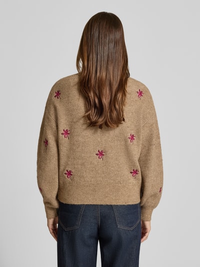 Vrouwenmodel draagt cardigan met oversneden schouders model 'FLEUR' van YAS, materiaalmix met katoen, loose fit, V-hals, knoopsluiting, ruglengte maat S 52 cm, mouwlengte maat S 52 cm, beige met roze geborduurde bloemen, ribtextuur, denim broek, volledige rugaanzicht