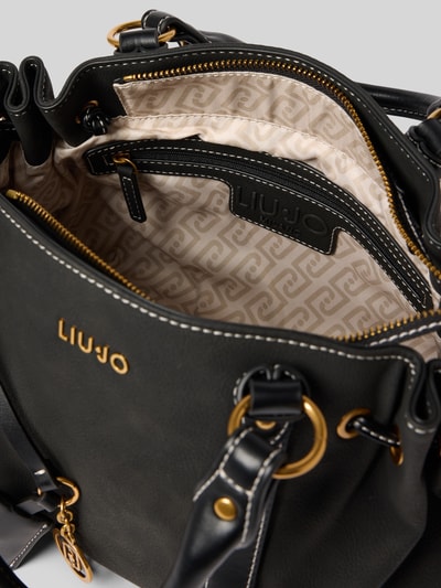 Produktfoto, Trunk in Leder-Optik mit Logo-Applikation Modell 'Ginesa' von Liu Jo White, Hauptfach mit Reißverschluss, schwarze Oberfläche, goldene Details, abnehmbare Tragehenkel und Schulterriemen, Innenfutter mit Muster, Maße: Breite 34 cm, Länge 21 cm, Tiefe 15 cm, Riemenlänge 112 cm.