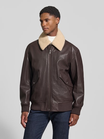 Männermodel trägt Regular Fit Lederjacke aus reinem Büffelleder Modell 'Jopeak' von BOSS Orange in dunkelbrauner Lederoptik, Ganzkörperansicht von vorne.