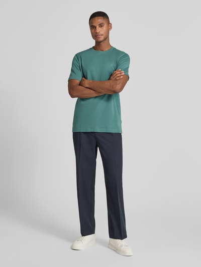 Männermodel trägt T-Shirt mit Label-Stitching Modell 'Priamo' von JOOP! Collection in Grün, reine Baumwolle, Regular Fit, Ganzkörperansicht von vorne.