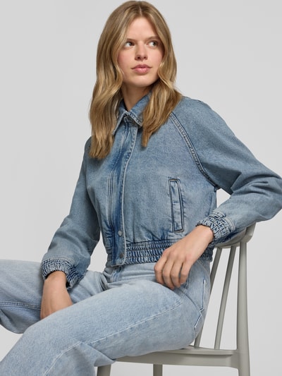 Frauenmodel trägt Relaxed Fit Jeans-Bomberjacke aus Baumwoll-Mix von Hugo Blue in Denim-Optik, Umlegekragen, verdeckter Reißverschluss, Nahaufnahme Oberkörper.