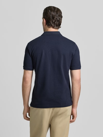 Męski model nosi Slim Fit Poloshirt mit Logo-Stitching von Gant z bawełny, krój slim fit, granatowy, golfowy kołnierzyk, widok całej sylwetki z tyłu.