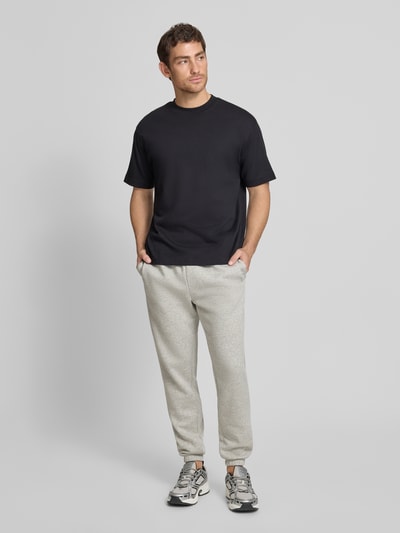 Männermodel trägt Sweatpants mit Logo und elastischem Bund von GAP aus Baumwoll-Mix in Regular-Fit, hellgrau, Ganzkörperansicht von vorne.
