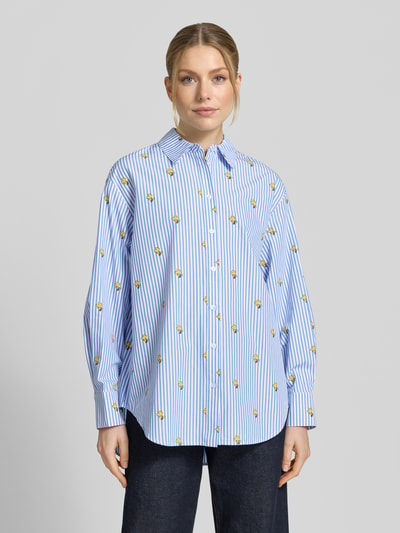 Modelka kobieca ma na sobie Oversized Hemdbluse aus reiner Baumwolle Modell 'JEPPERMINT SNOOPY' od Essentiel Antwerp, niebiesko-białe paski z nadrukiem, bawełniana popelina, widok całej sylwetki z przodu.